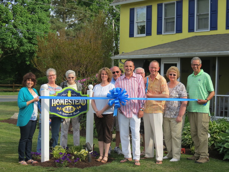 Cutting the ribbon for The Homestead B & B are in back (l-r) Dennis Crowley and Drenning Sweigart (partially blocked); in front, Elsa Munos, Rehoboth-Dewey Chamber; Becky Carney, Delaware Beach Book; Shirley Baum; Jerri Miller; David Brinton; Joe Sterner; Tina Sterner; and Marvin Carney, Delaware Beach Book. SOURCE SUBMITTED