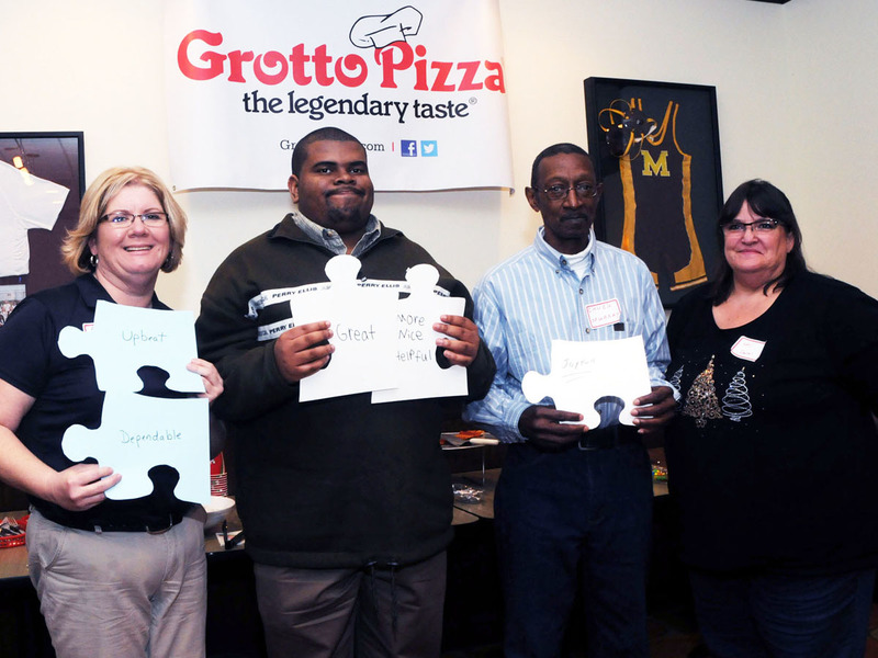Holding up puzzle pieces with words describing the program participant and words describing co-workers from Grotto Pizza in Dover are (l-r) Audrey Swain, general manager Grotto Pizza Dover; Jordan Little, POW&R participant/Grotto mployee; Chuck Murray, Grotto co-worker; and Lori Naylor, POW&R direct support professional. BY STEVEN BILLUPS