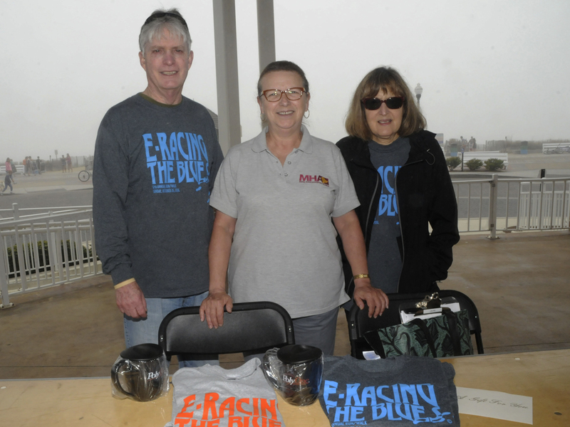 Waiting for the walkers to return to the Bandstand are (l-r) volunteer John Hammett, and Mental Health Associates Director of Communications and Development Laurie McArthur and Myra Kramon. BY STEVEN BILLUPS
