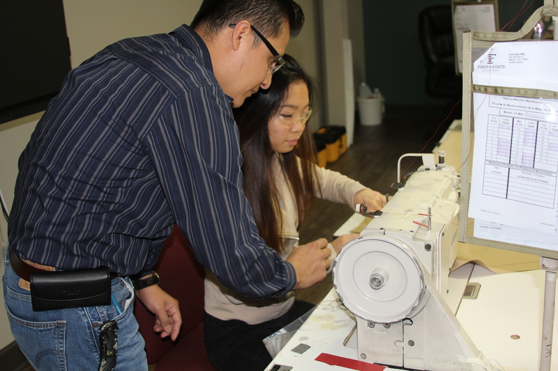 Sophomore Jane Yang gets some pointers about the industrial sewing machines from Younger Dominguez, a supervisor at First State Manufacturing. BY MELISSA STEELE