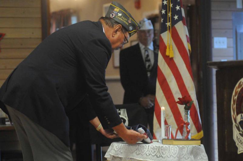 The service started with the description of the symbolism of the items on the POW-MIA table. AMVETS Trustee Gene Bradley reverently lays a flag on the table. BY STEVEN BILLUPS