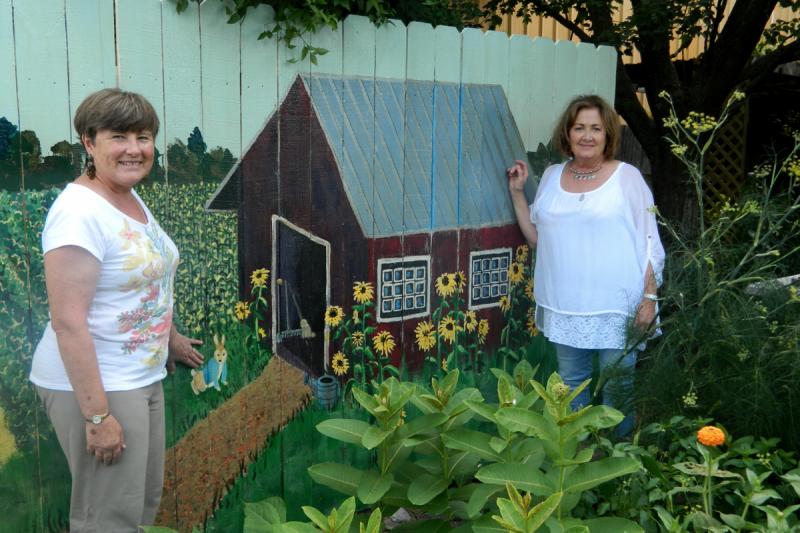 Artists Eddie Filemyr, left, and Valerie Hammer pose in front of the fence they designed and painted. SUBMITTED PHOTO