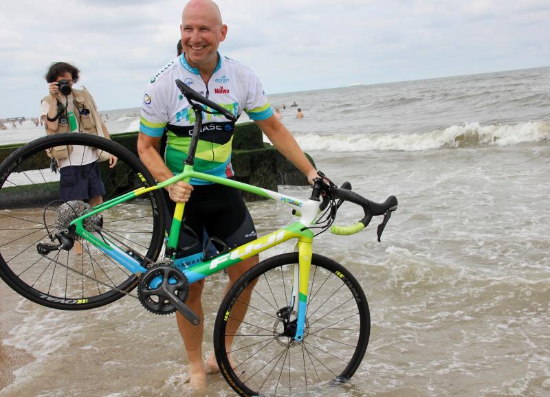 Former Delaware Gov. Jack Markell dips his front tire in the Atlantic Ocean at Rehoboth Beach to signal the completion of his 3,800-mile trek across the United States. DENNIS FORNEY PHOTO
