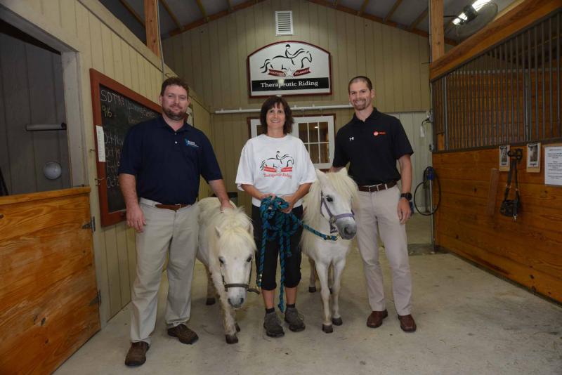 In the stable with ponies Nayah, left, and Angel are (l-r) Atlantic Refrigeration Vice President Jamie Nickerson, SDTR board member and instructor Kelly Boyer, and Trane Territory Manager Joe Capen. Every year Atlantic likes to support nonprofits and with Trane as its partner, chose to support SDTR this year. SDTR