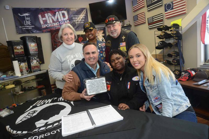 The Flag leaders of the tour gather around Sen. Ernie Lopez, R-Lewes, with the official Fag in an inscribed box. Shown in back are (l-r) Rosely Robinson, Delaware Flag Tour director; Carol Holtmeyer, Flag Leader; and John Peterson, Flag Escort. In front are Lopez; Becky Beckford; and Becca Bristow, Miss New Castle County. On the table on the flag is a book signed by individuals from every stop on the tour of the flag that is destined to end its journey at the Smithsonian Institute in Washington, D.C. POW MIA Flag Tour