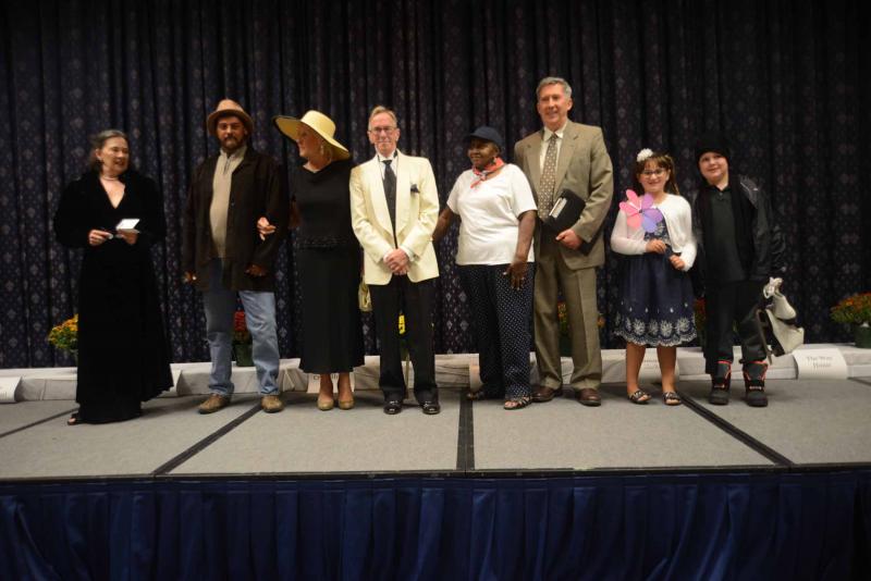 The models from the thrift store fashion show make a curtain call after the show. Shown are (l-r) Serena Miles, Kevin Morris, Donna Minton, Eddie Ward, Theria Brasty, Bob Harrison, Summer Fusco and Alex Munson. All Saints’ Celebration 2018