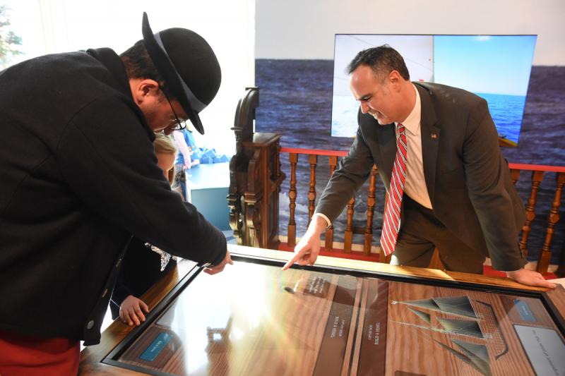 Marcos Salaverria, director of development for the Lewes Historical Society helps a youngster build a boat as Sen. Ernie Lopez looks on.