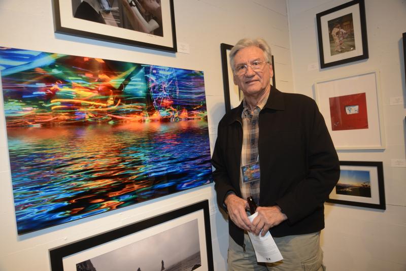 Peter Treiber stands with his night-shot titled “Eternal Luminescence 63375.” The image was photographed at a Baltimore festival and is mounted on aluminum. RAL Juried Photo exhibit