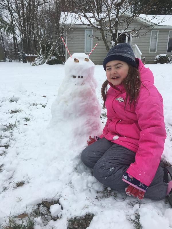 McKenzie Russell’s face shows pure joy as she builds a snowman in Milton.