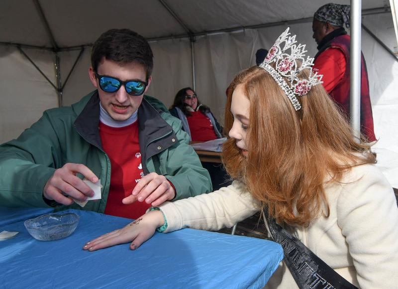 SODE volunteer Bradley Beamer, left, applies a Polar Bear tattoo to Pure International Pageant Young Miss Delaware Sweetheart Amelia Kramer. DAN COOK PHOTO