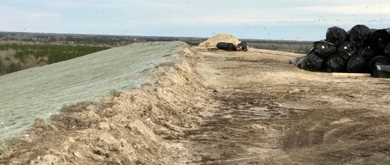 The raw garbage in the cells is ultimately capped with four feet of dirt and impermeable geotextile materials which are all part of keeping the garbage from polluting, and collecting methane gas generated by the deteriorating garbage to power en electricity-generating plant on the site. Rolls of the geotextile materials used to cap the site are in the right of this photograph, while the left side of the photo gives an idea of the thickness of the dirt and geotextile cap, and the seeding material on top. The dirt comes from privately owned pits in the vicinity.