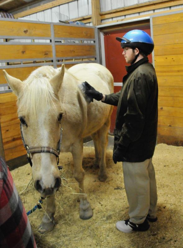 Anthony LaRose brushes down Willy before taking a ride in the Southern Delaware Therapeutic Riding indoor arena. RON MACARTHUR PHOTO