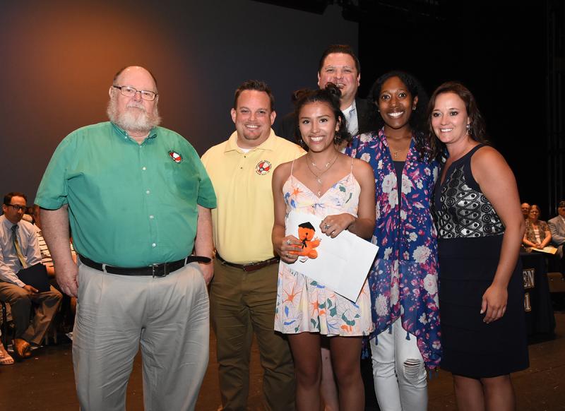 Kelly Buruca, center, is shown with (l-r) Dickie Mitchell and Christopher Berg of Rehoboth Beach Bears, Brandon Townson and Shaheda Pine of Delaware School Counselors Association, and Cape Principal Nikki Miller.