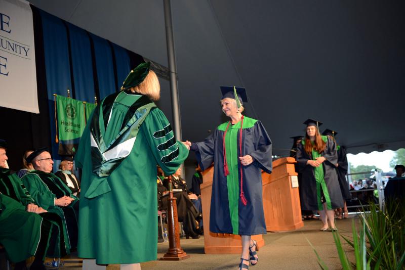 Brenda Baker-Mack from Lewes shakes the hand of Board of Trustees Vice Chair Patti Grimes prior to receiving her diploma. Del Tech Commencement