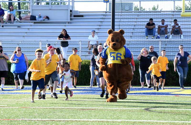 Buddy Bear leads the buddies onto Tubby Raymond Field to meet their football players and cheerleaders.