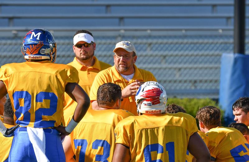 Gold assistant coach Mike Tkach goes over pregame strategy with his linemen.