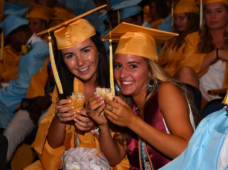 Chloe Schaeffer, left, and Jillian Seker get some last-minute nourishment while awaiting the processional lineup.