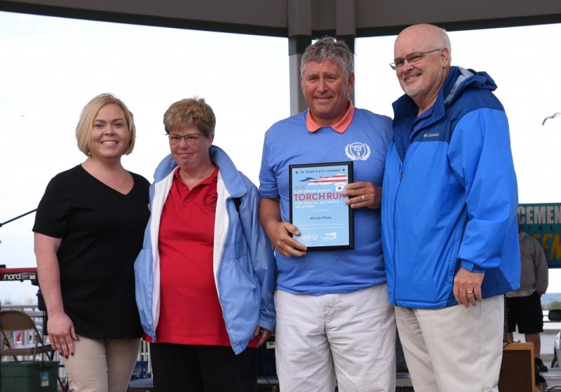 Nicola Pizza in Rehoboth Beach is honored as a long-time sponsor of the Torch Run and Special Olympics. At the presentation on the Bandstand are (l-r) Kelly Munyon of Nicola Pizza, Suzie Schaible of Sussex Riptide, Nick Caggiano, owner of Nicola Pizza, and Greg Nolt, event coordinator who has been involved since the inception of the Torch Run.