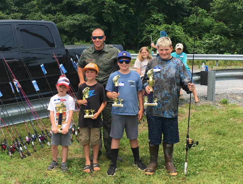 Sussex County fishing tournament winners at Ingrams Pond near Millsboro are in front (l-r) John Timmons V, first place ages 4-7; Cohen Betts, first place ages 8-11; Camrin Croney, first place ages 12-15; and Sussex winner Like Hitchens. In back is DNREC Fish & Wildlife Natural Resources Police Cpl. Adam Roark. SUBMITTED PHOTO