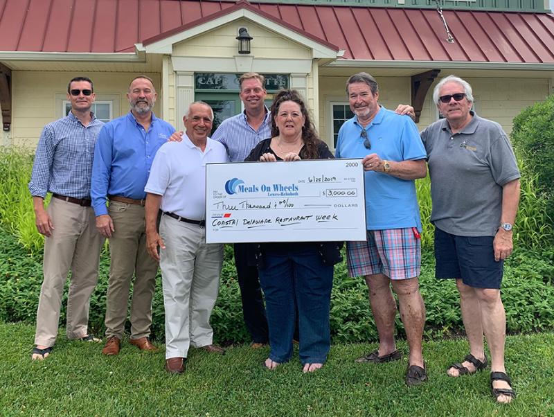 Coastal Delaware Restaurant week presents a $3,000 donation to Meals on Wheels Lewes-Rehoboth on the doorstep of the Cape Gazette in Lewes. In attendance were (l-r) Cape Gazette Co-Publisher and General Manager Chris Rausch; Clark Service Group President and CEO Glenn Clark Jr.; Meals on Wheels Lewes-Rehoboth board members Harry Papaleo and David Humes; Meals on Wheels Executive Director Kathy Keuski; Governing Board President John Wolfle; and Meals on Wheels board member and Restaurant Week sponsor Bob Yesbek of Rehobothfoodie.com. SUBMITTED PHOTO