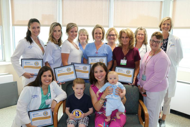 Laura Parsons celebrates the excellent care she received during the births of her three healthy sons at Beebe Healthcare. Shown are in back (l-r) Dr. Holly McKiel, Jenn Rice, Anna Merrick, Nurse Manager Lisa Klein, Crystal Reynolds, Nancy Hastings, Vicky Mallet, Neonatal Nurse Practitioner Nancy Forsyth, Teresa Fritz, and Executive Director of Women’s Health Bridget Buckaloo. In front are Dr. Angela Caswell-Monack, Rex Parsons, and Laura Parsons with Teddy. SUBMITTED PHOTO