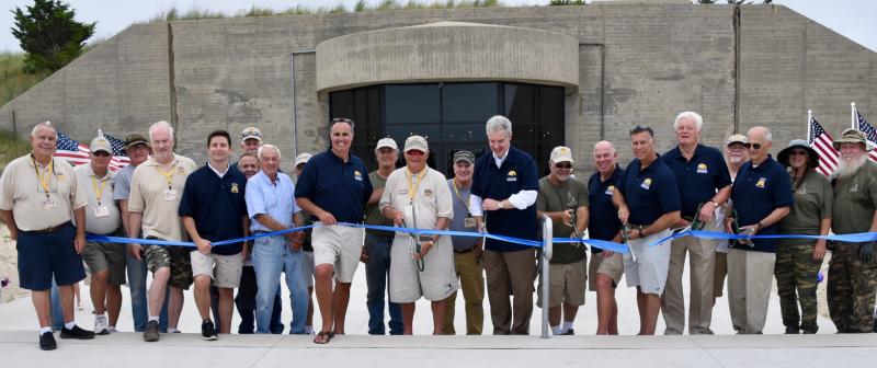 A large group of officials and volunteers prepares to cut a ribbon to dedicate the Great Dune Overlook.