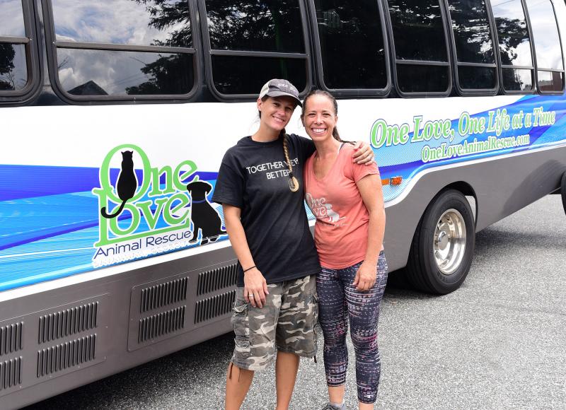 Grass Roots Rescue’s Karli Crenshaw, left, poses with One Love Animal Rescue CEO and founder Karrie Bulski after the dogs were processed and their health was assessed.