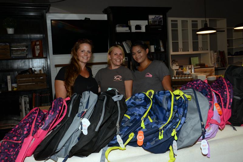 Gathered behind a few of the donated backpacks are organizers and sponsors (l-r) Jami Ferro, Allserve owner; Brittany McCabe, McCabe Home Innovations owner; and Mali Belcamino, Meibaum Excavation. Backpacks, Haute Living