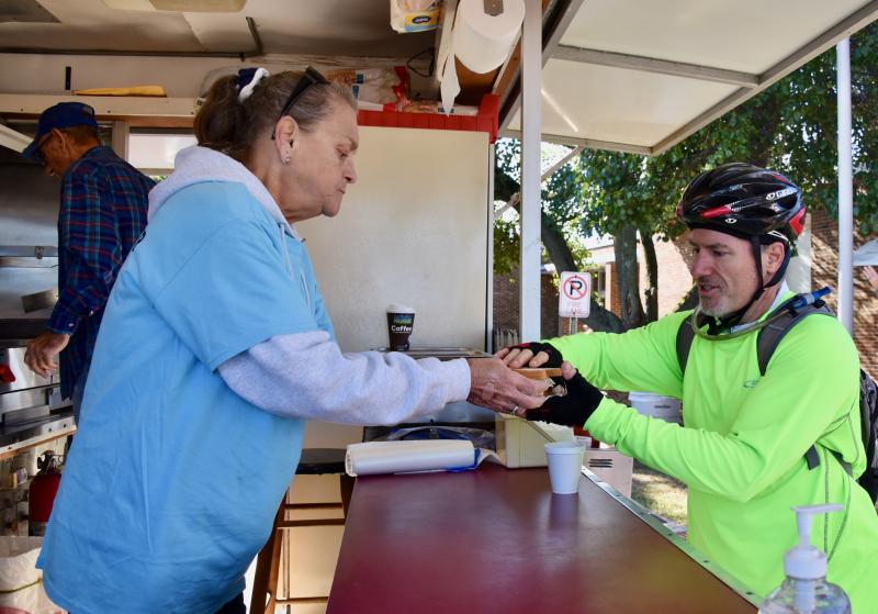 Rebekah volunteer Ruth Scott hands a hot scrapple sandwich to rider Tom Law of Raleigh, N.C., at a rest stop at Milton’s H.O. Brittingham School. Members of the Odd Fellows and Rebekahs have been manning a food station for years.