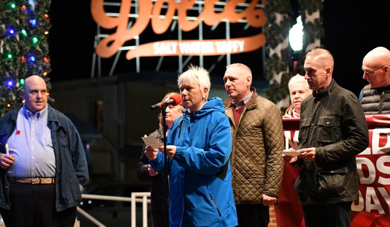 Cathin Bishop reads, “Tonight we carry a candle to celebrate long-term survivors of HIV and AIDS.”