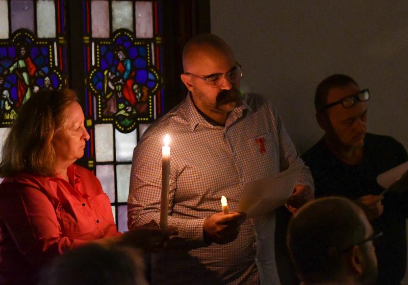 Laurie Kuebler holds a candle as Sal Seeley reads names of people who have died of AIDS.