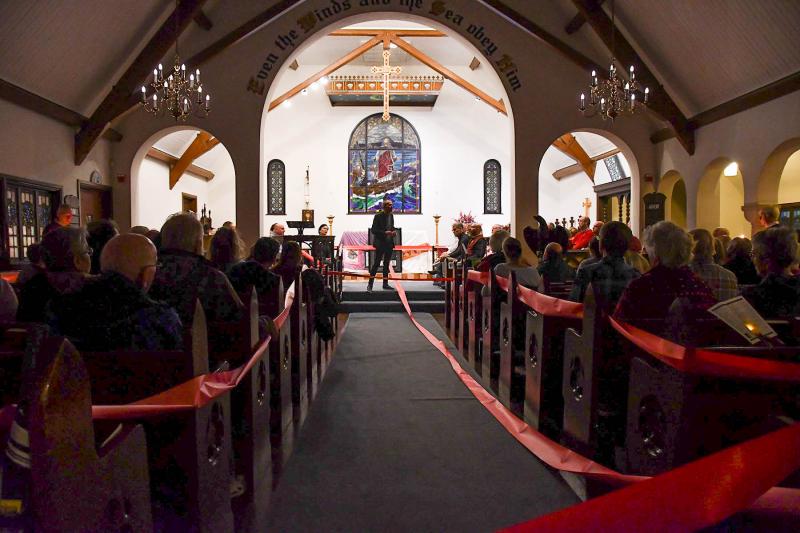 CAMP Rehoboth founder Murray Archibald wrapped the observers gathered at All Saint’s with a wide red ribbon and said the red ribbon tied us together into community and despite our differences, we are one.
