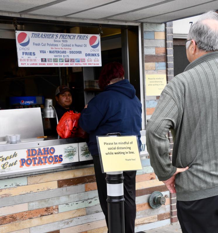 On March 21, Thrasher’s French Fries, near the Rehoboth Beach Boardwalk, warns patrons to keep their distance. The day before, thanks to record temperatures, people crowded the area throughout the day. RON MACARTHUR PHOTO