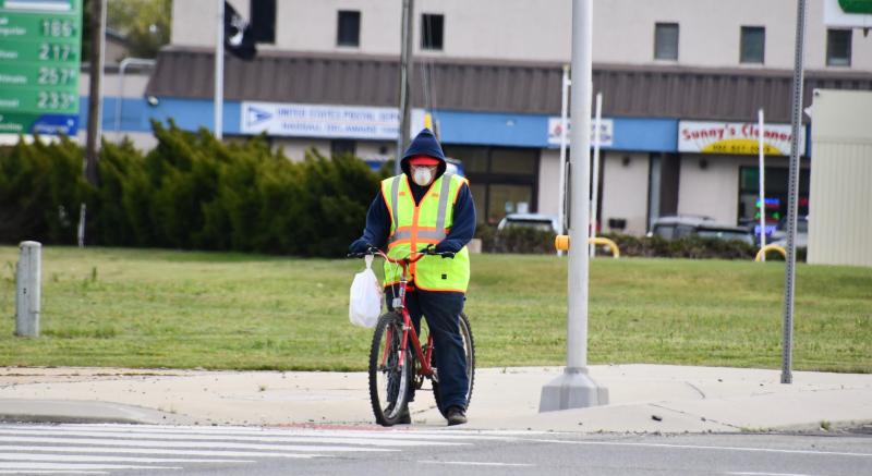 A masked bicyclist stops before crossing over Savannah Road at the Five Points intersection.