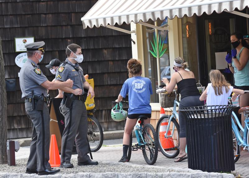 Lewes Police officers, including Police Chief Tom Spell, left, were on Second Street to ensure those waiting in line stayed an appropriate distance apart. NICK ROTH PHOTO