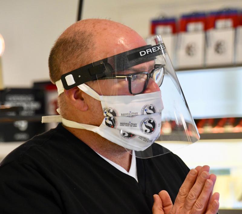 Bad Hair Day owner Drexel Davison, wearing protective gear, informs a client of the new protocols in place in the salon.