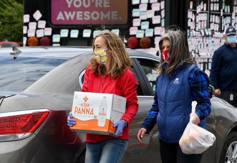 Volunteer Heather Manlove, left, and Schell Brothers’ Alyssa Titus are busy loading vehicles during a food distribution in Seaford.