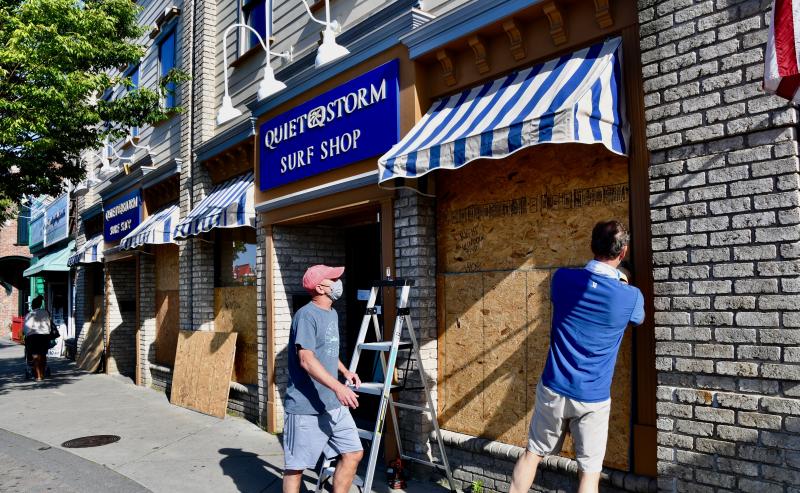 Quiet Storm staff on Rehoboth Avenue are taking no chances as they board up store windows. The planned protest was called off, but peaceful protesters gathered anyway.