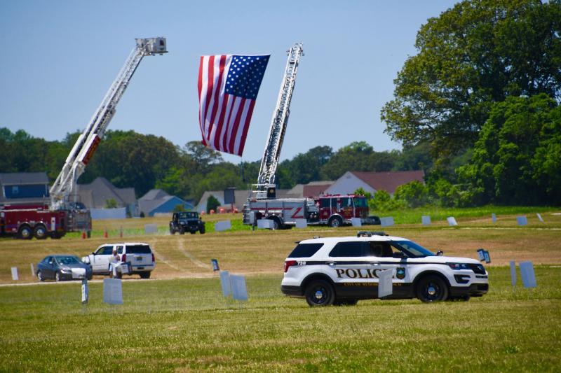 Drivers enter Hudson Fields under a large U.S. flag flown in honor of the graduates by the Lewes and Milton fire departments.