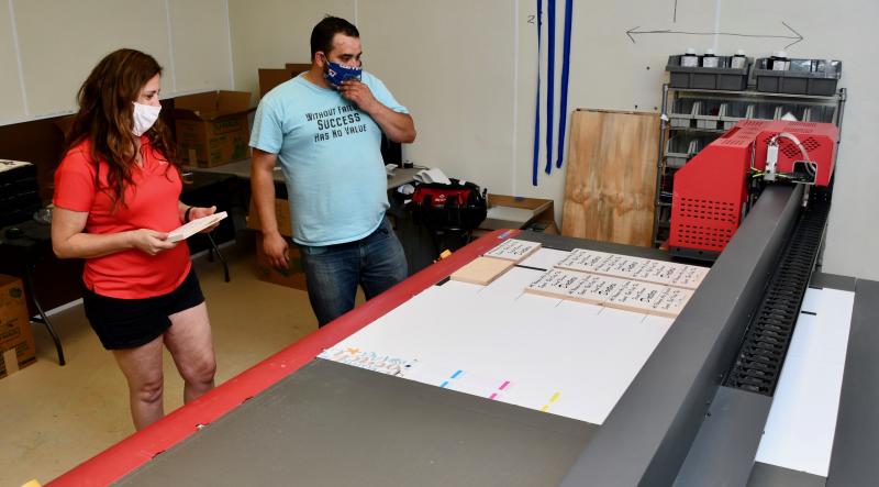 Co-president Jennifer McMillan looks at new signs made on a state-of-the-art printer with employee Chris Brazell.