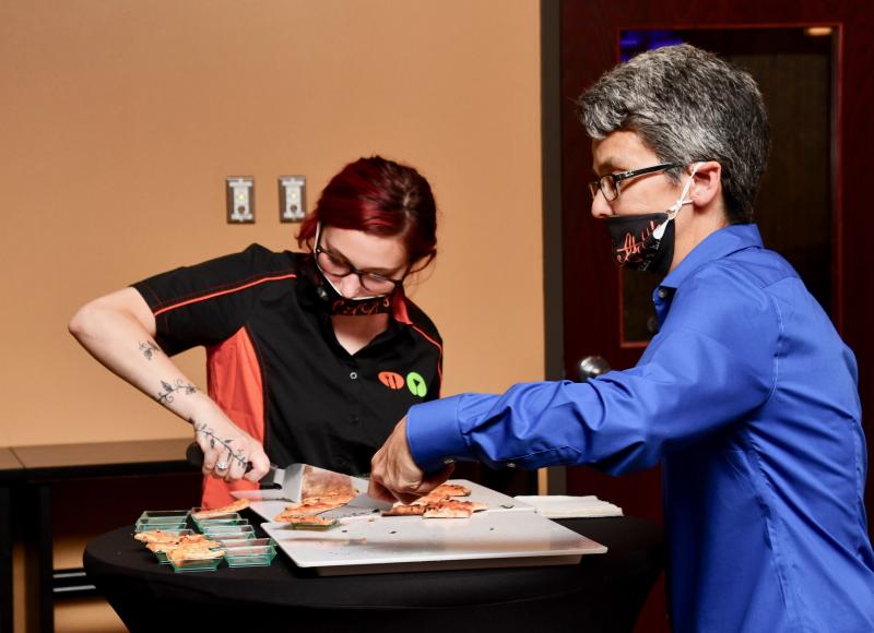 Lefty’s employees Samantha Campbell, left, and Karen Dawson cut pizza for people attending a VIP and friends event June 18.