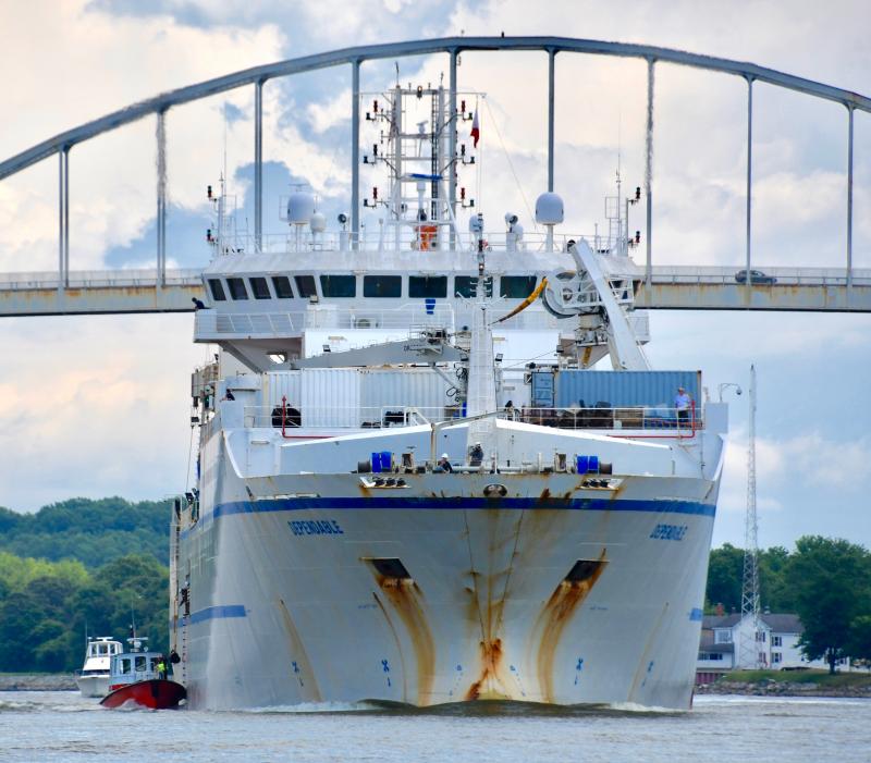 Dwarfed in size, a Maryland pilot boat comes along side the cable-layer Dependable as it crosses under the Chesapeake City bridge.