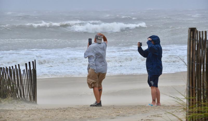 A couple braves blowing sand and wind to take photos of the waves in Rehoboth Beach. RON MACARTHUR PHOTO
