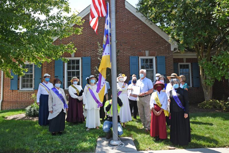 Lewes Mayor Ted Becker, members of the Zwaanendael Women’s Club and Col. David Hall Chapter of the Daughters of the American Revolution, and city council and staff gather as the Suffragette Flag is raised outside city hall.