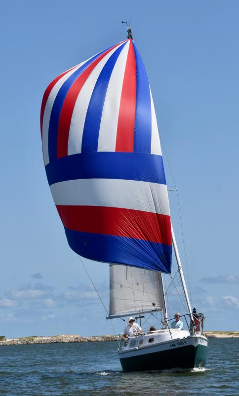 With its red, white and blue spinnaker flying, Pearl begins the downwind leg of the annual LYC Labor Day Breakwater Race. The boat, skippered by Dave Cerney, and crewed by Kathy McDaniel and Mike Goetz, won the traditional race.