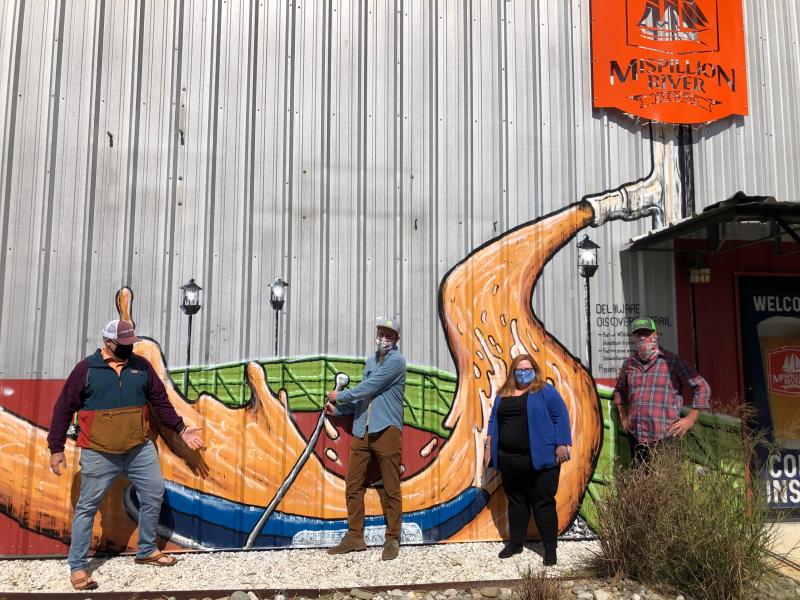 Delaware Tourism Office has launched the Delaware Discoveries Trail, a series of nine murals painted by local artists on buildings statewide. Standing next to the mural at Mispillion River Brewing Company in Milford are (l-r) Tom Little of Developing Artist Collaboration, artist Michael Johnson, Liz Keller of Delaware Tourism, and Mispillion owner Eric Williams. RYAN MAVITY PHOTO