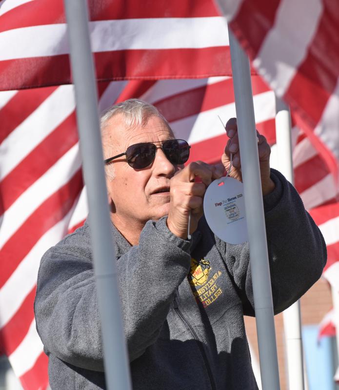 Lt. Col. Ronald Erale of the Cape JROTC program places a medallion on a flag.