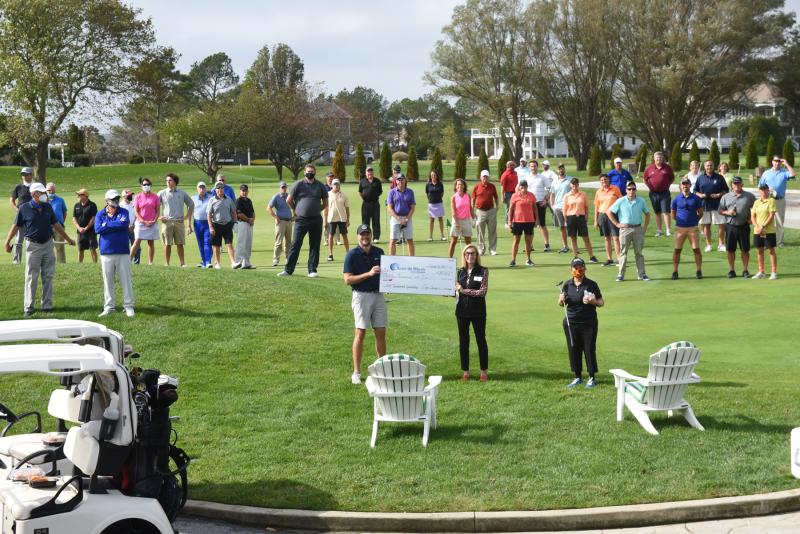 Clay Serman, Meals on Wheels Lewes-Rehoboth board member and golf chairman, and Ann Bailey, MOWLR board member and president, show off a check for more than $32,000 raised at the annual golf tournament. They are surrounded by the socially distanced golfers who participated in the tournament. NICK ROTH PHOTO
