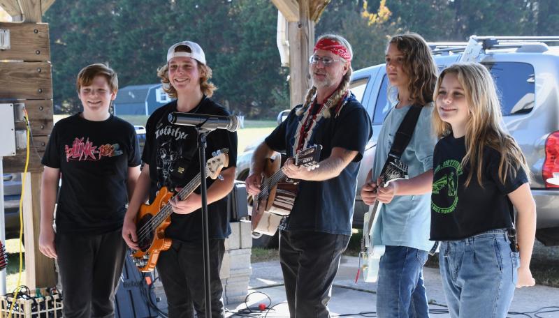 The first two acts performing at the Toys for Tots kickoff pose together so fans can take photos. In the middle is Shotgun Willey with members of the band Hope for Success (l-r) Alex Fitzkee, Drew Fitzkee, Jasper Isaacs and Elaina Marsch.