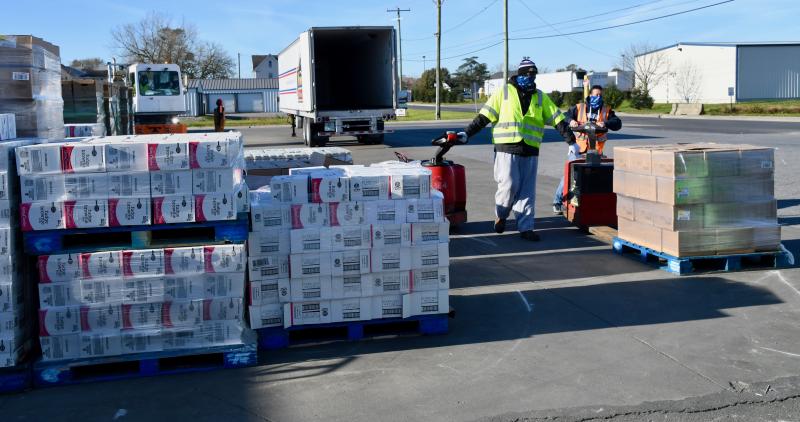 Crates of canned goods and food are ready to go under the packing tent while prepared boxes are ready to load in a refrigerated trailer.
